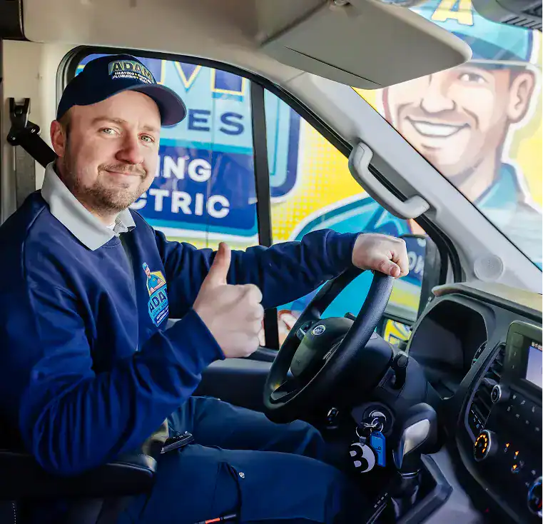 A man in uniform sits in a van’s driver seat, giving a thumbs-up. A company logo and illustrated advertisement are visible outside the window.